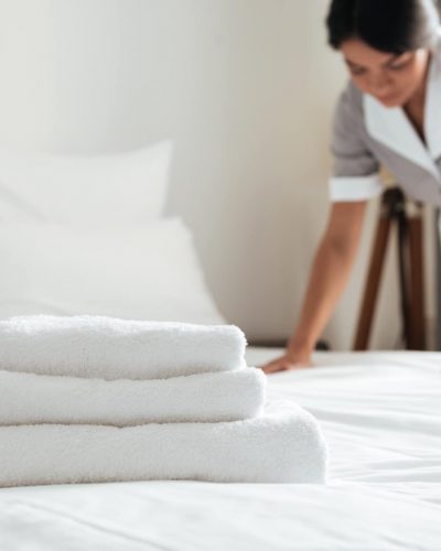 Young hotel maid making the bed with clean fresh towels